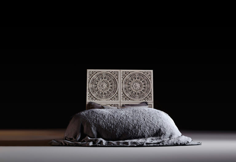 Baroque-styled bed with a carved wooden headrest and a silk embroidered blanket on a dark background 3D visualization